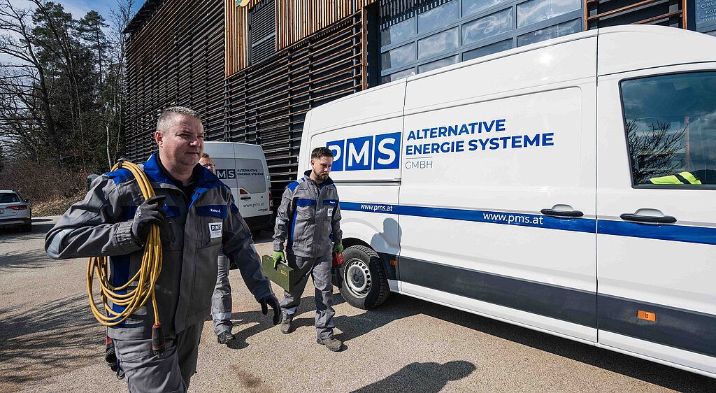 Das Serviceteam der PMS Alternative Energie Systeme vor dem Firmenbus, im Hintergrund ein Heizkraftwerk