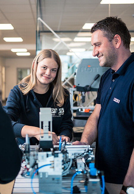 Ein Lehrmädchen arbeitet an einem Modell und der Lehrlingsausbilder beobachtet sie dabei