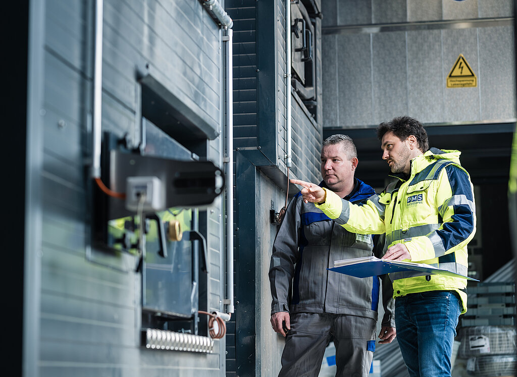 Servicemitarbeiter der PMS Alternative Energie Systeme beim Überprüfen eines Heizkessels