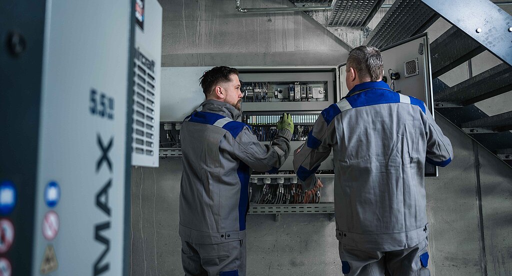 Zwei Servicemitarbeiter vor einem Schaltschrank in einem Heizkraftwerk