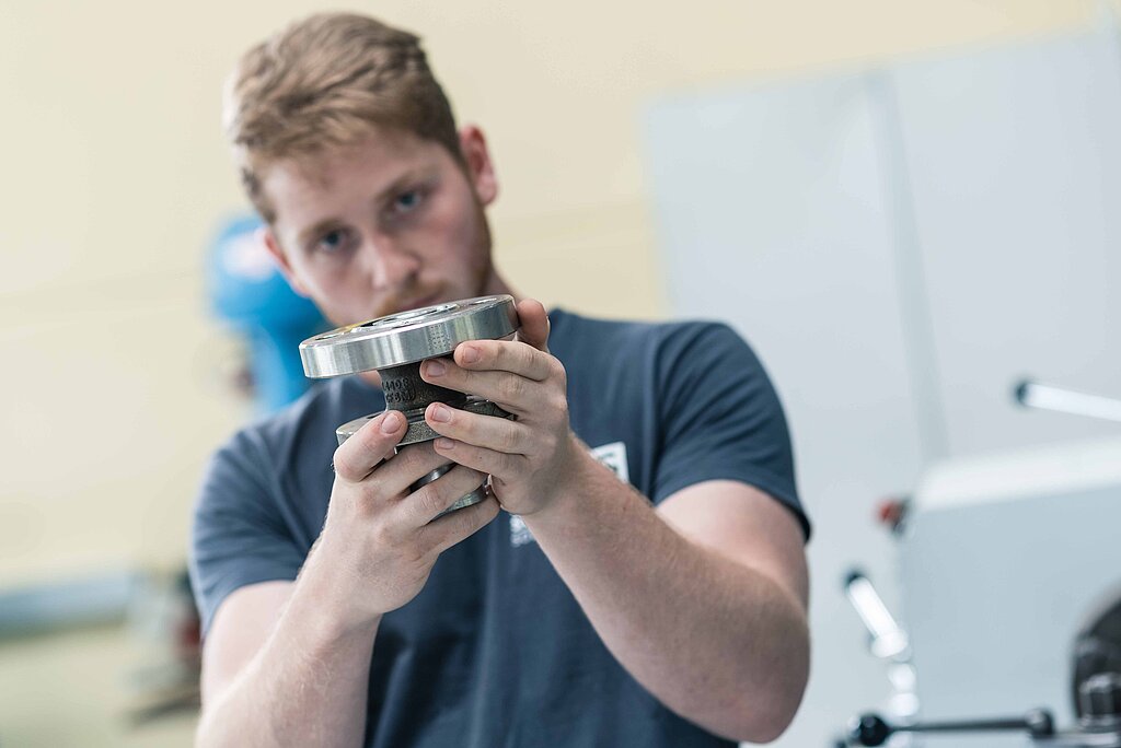 Ein Mitarbeiter der PMS valveTec hält ein Ventil in den Händen und begutachtet es