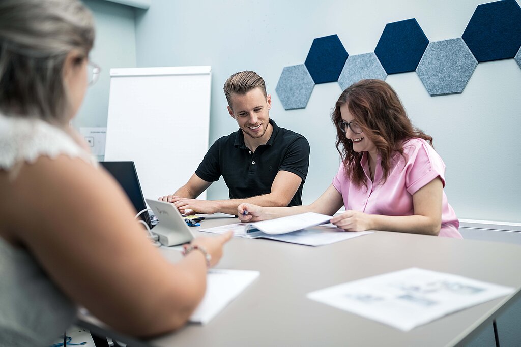 Mitarbeiter der PSI Powerful Solutions beim Prüfen von Unterlagen und Arbeiten am Laptop im modernen Besprechungsraum
