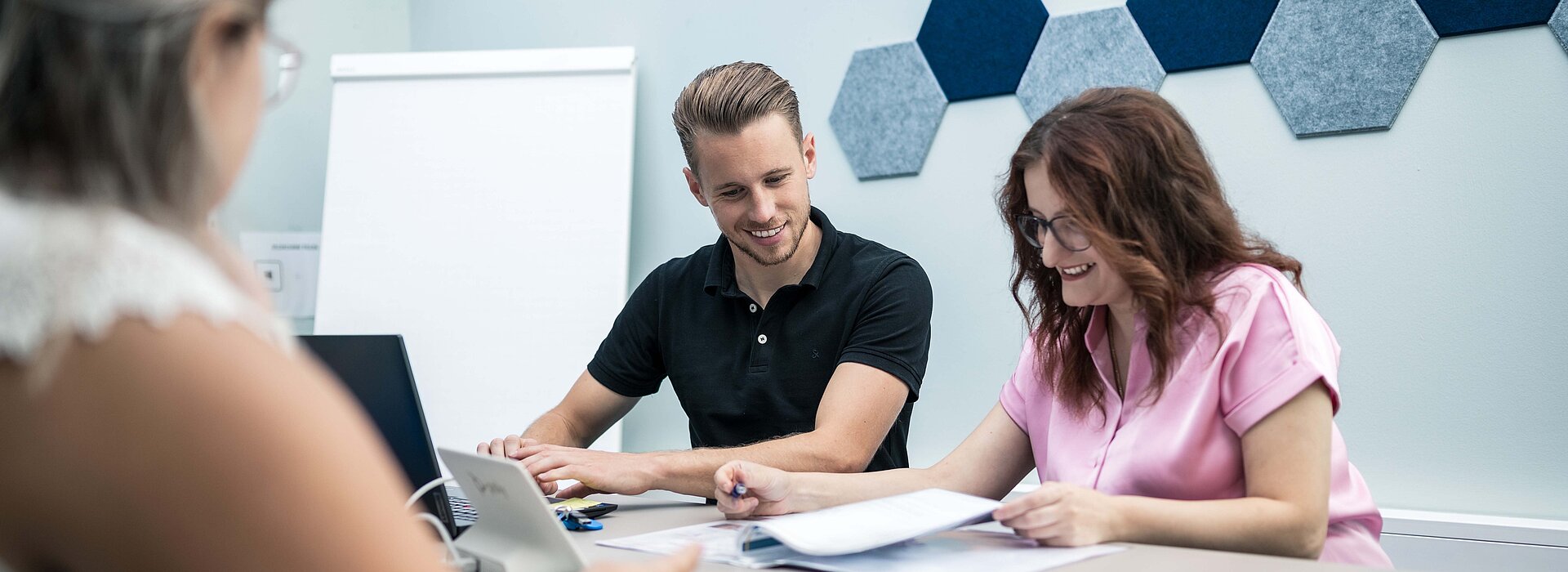 Mitarbeiter der PSI Powerful Solutions beim Prüfen von Unterlagen und Arbeiten am Laptop im modernen Besprechungsraum