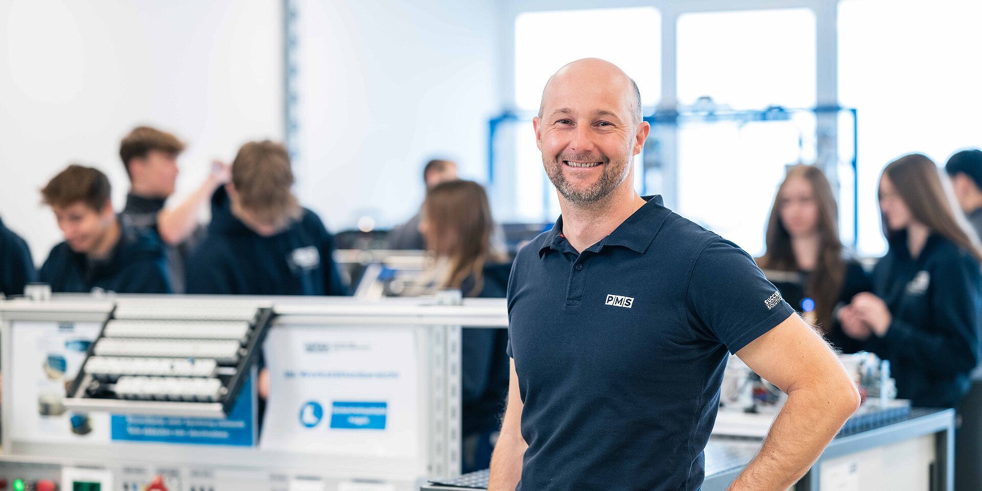 Herwig Fritzl - Lehrlingsausbilder bei PMS in der Lehrwerkstäte, im Hintergrund die Lehrlinge beim Arbeiten