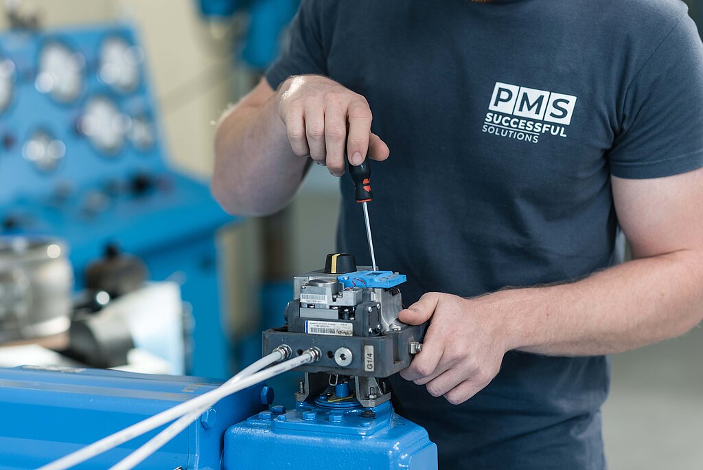 Ein Mitarbeiter der PMS valveTec schraubt an seiner Werkbank an einer Armatur