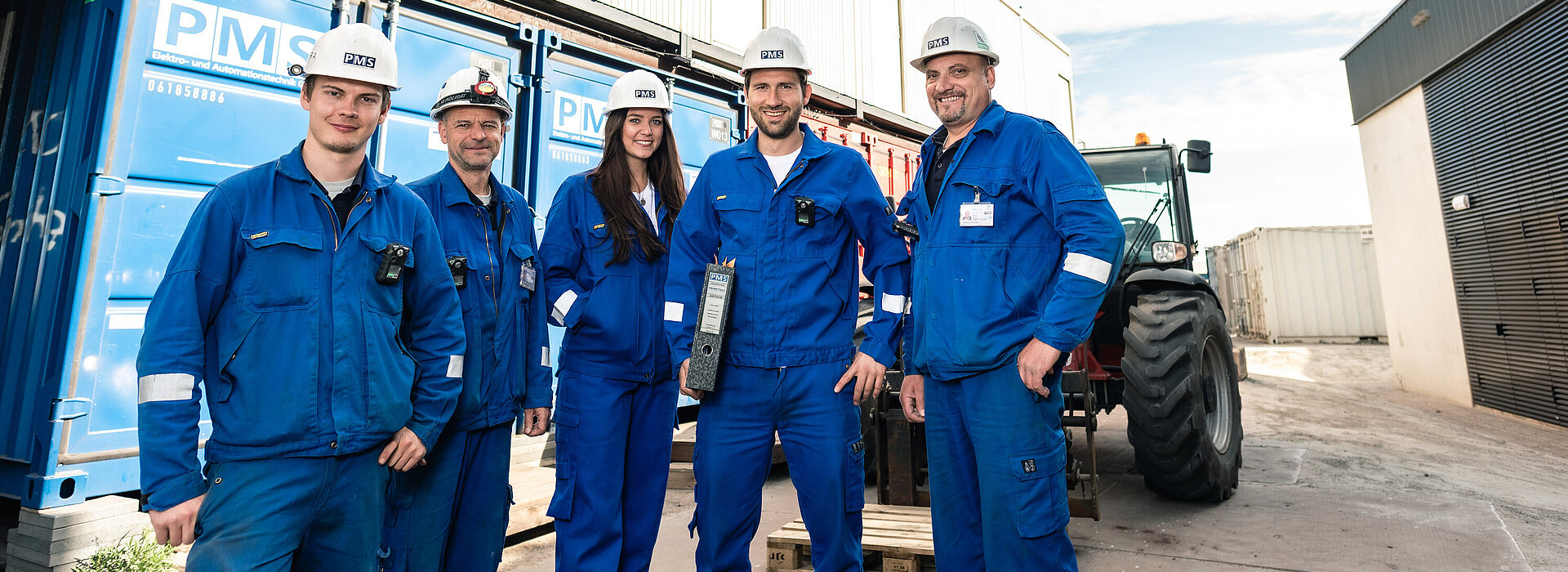 Projektmannschaft in Arbeitsmonturen vor einem Container auf der Baustelle