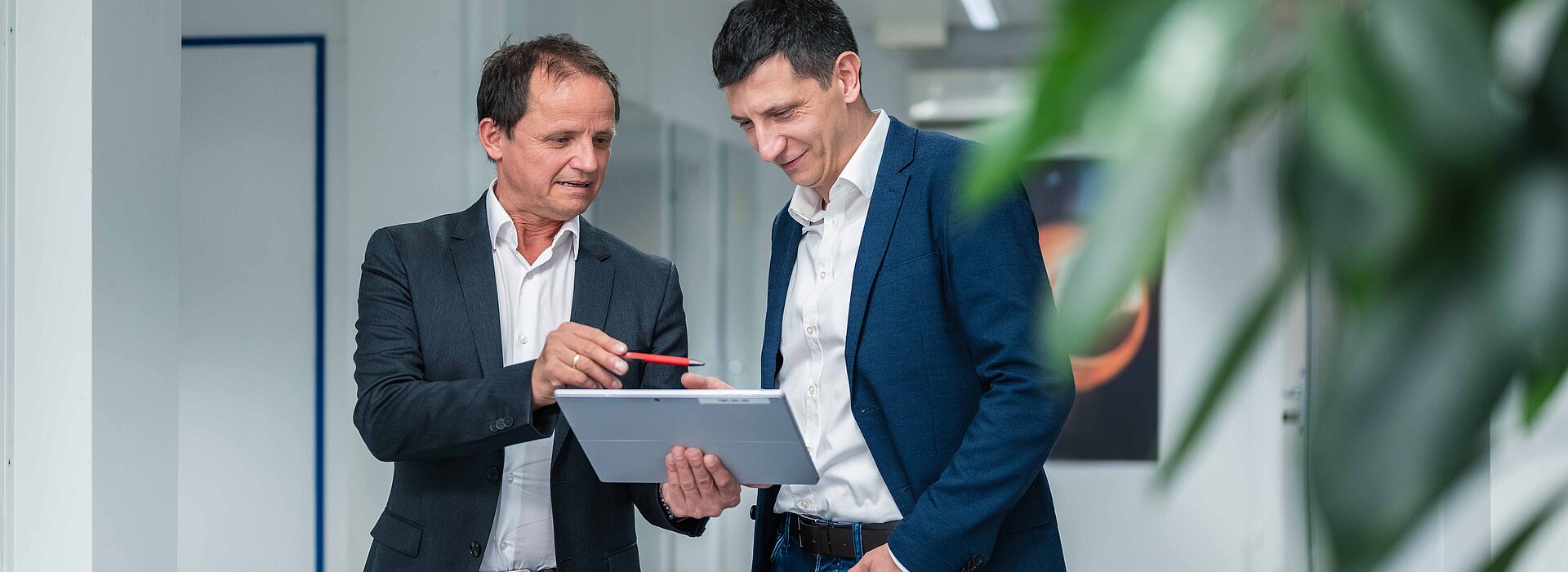 Die Geschäftsführung der PMS Alternative Energiesysteme beim Gespräch über ein Tablett gebeugt im Büro der AES