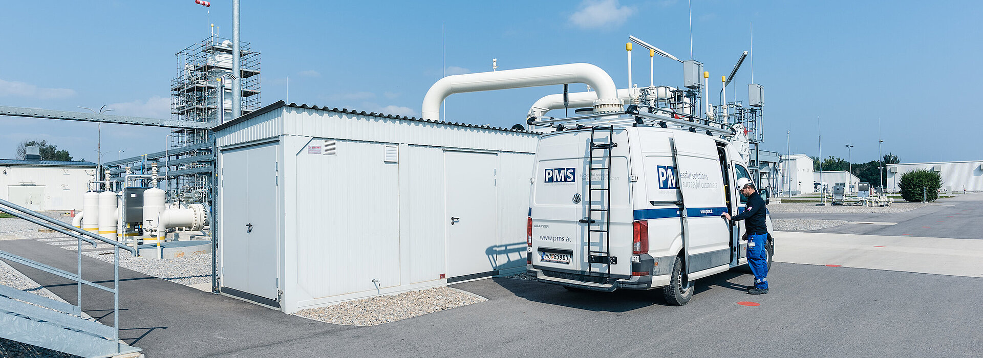 Ein Mitarbeiter öffnet die Türe eines PMS Busses, im Hintergrund eine Gasmessstation bei herrlichem Wetter