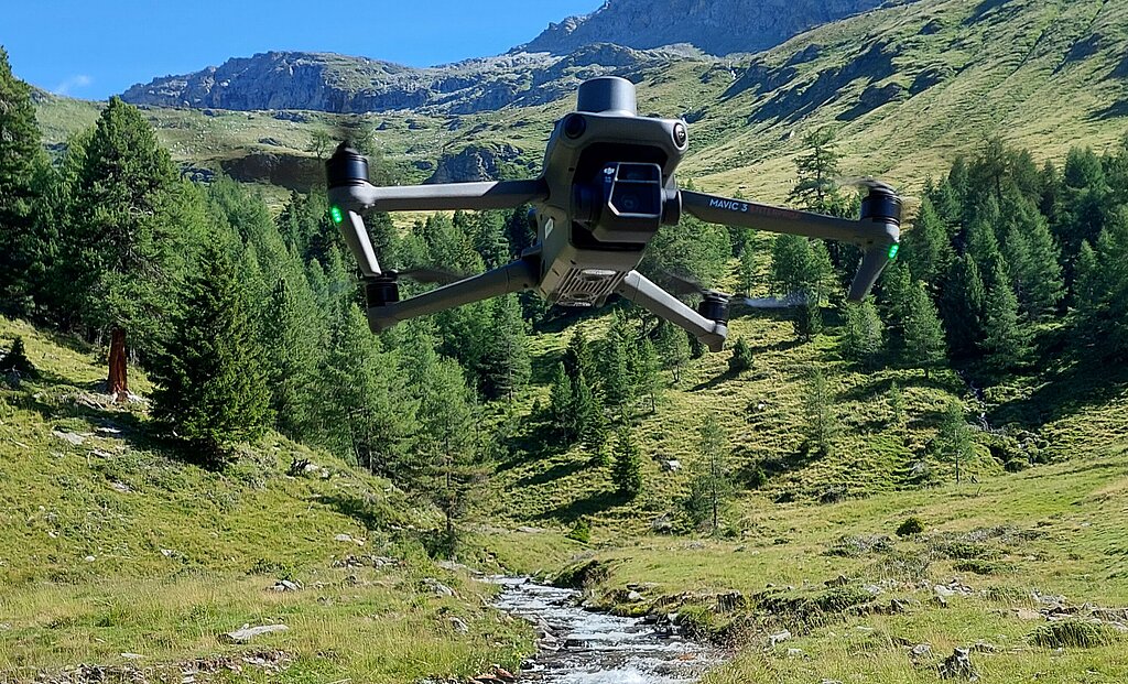 Eine Drohne über einem Wildbach in einer herrlichen Almlandschaft 