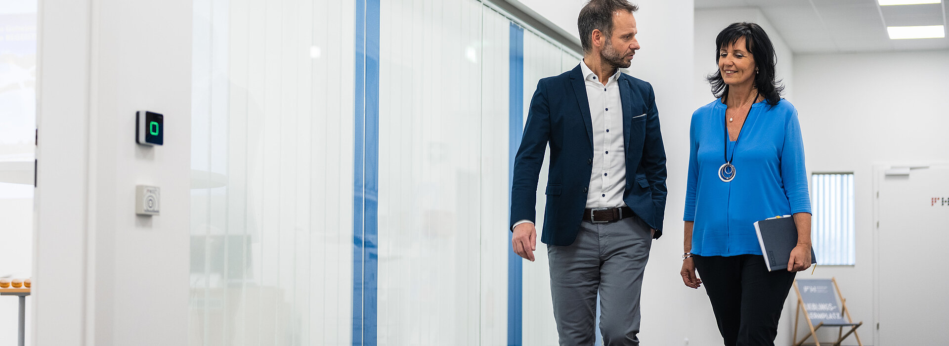 Zwei PMS Technikum Mitarbeiter schreiten den Gang der Innovationswerkstatt entlang und unterhalten sich