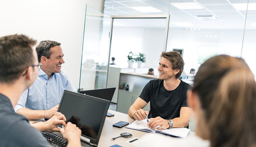 Eine Gruppe von PMS Mitarbeitern in einer Besprechung im modernen Besprechungsraum
