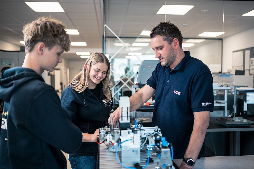 Lehrlingsausbilder mit zwei Lehrlingen in der PMS Lehrwerkstätte.